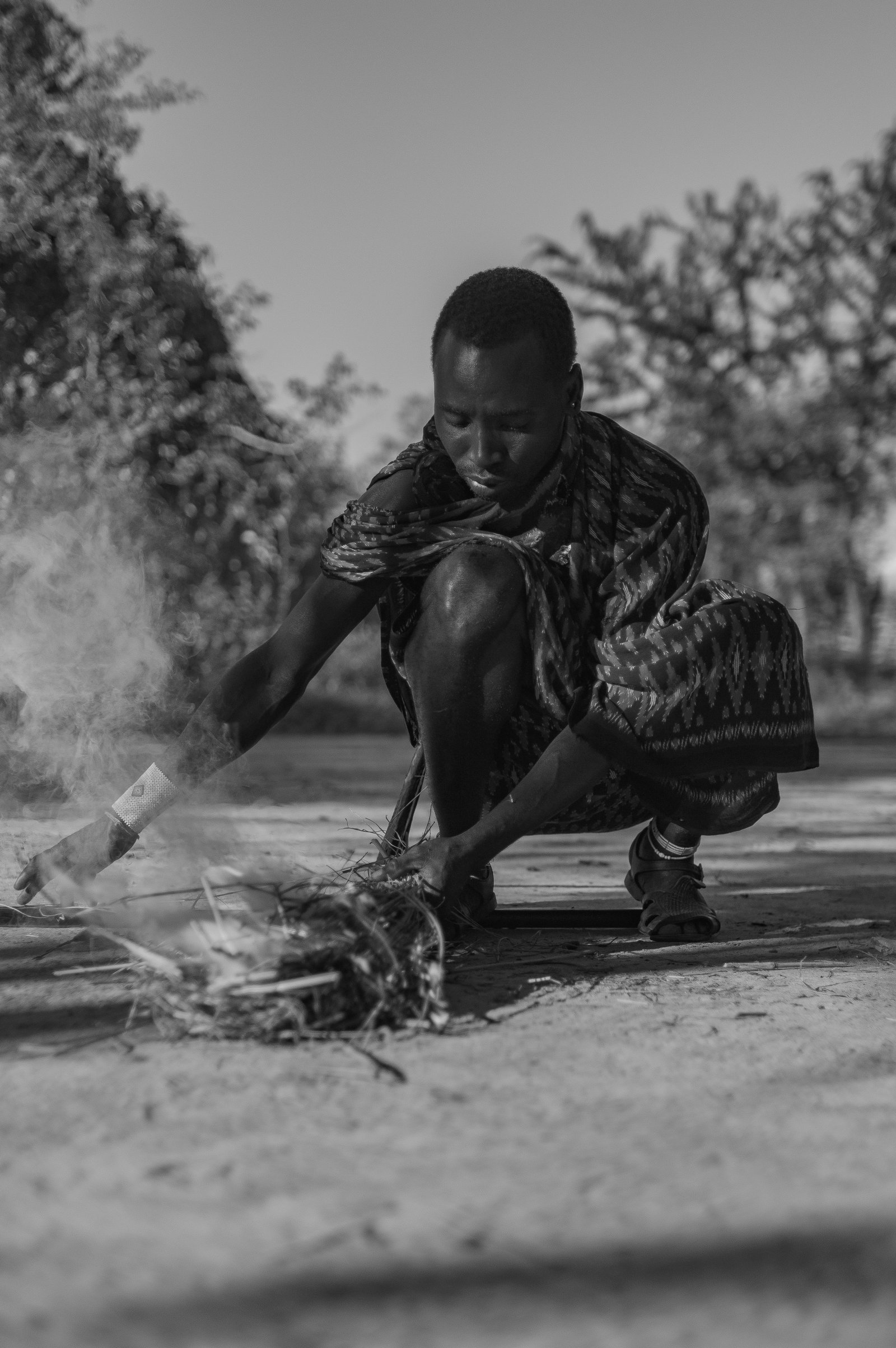Man demonstrating traditional fire-starting technique in the African bush, Tanzania