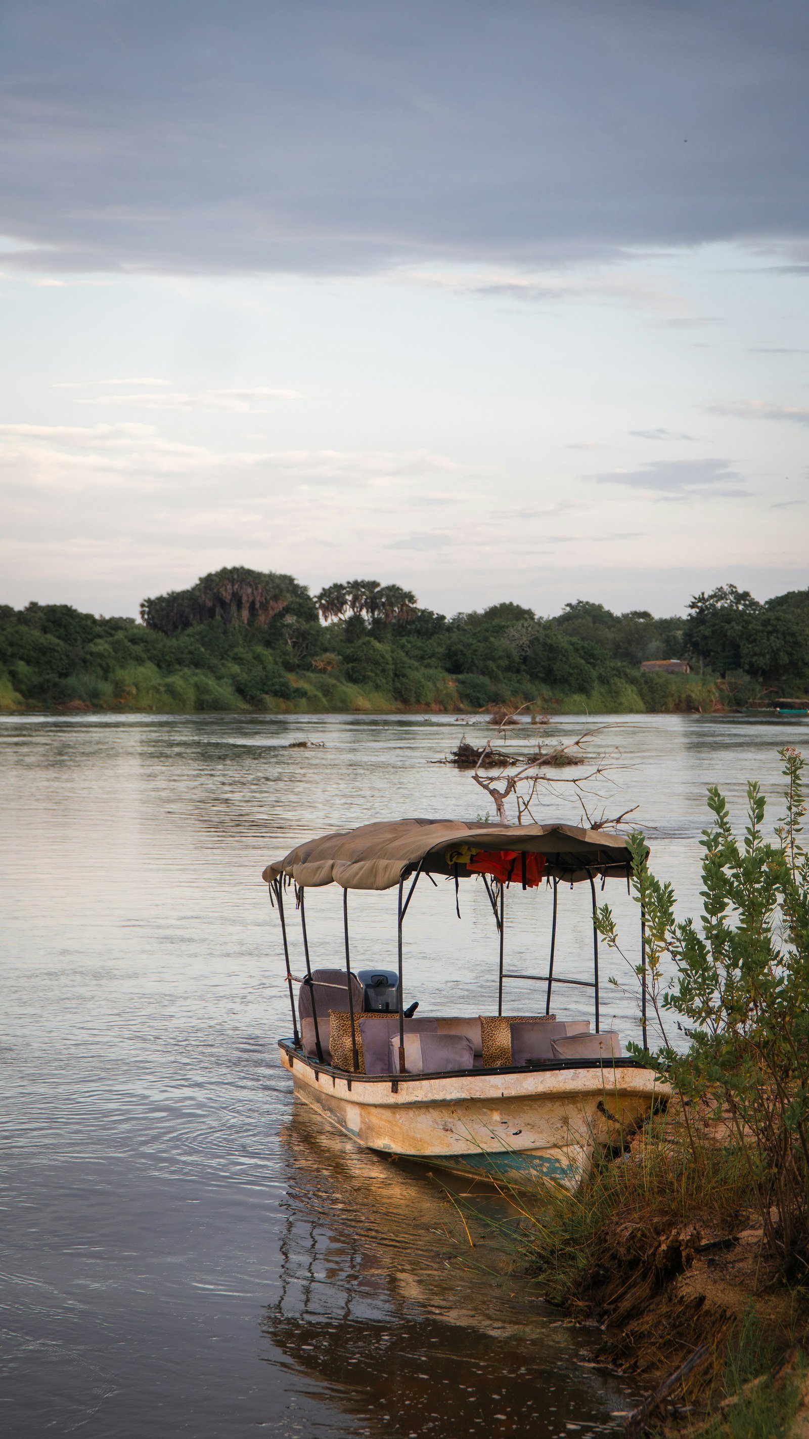Small motorised safari boat moored on the wide Rufiji River at dusk, Tanzania