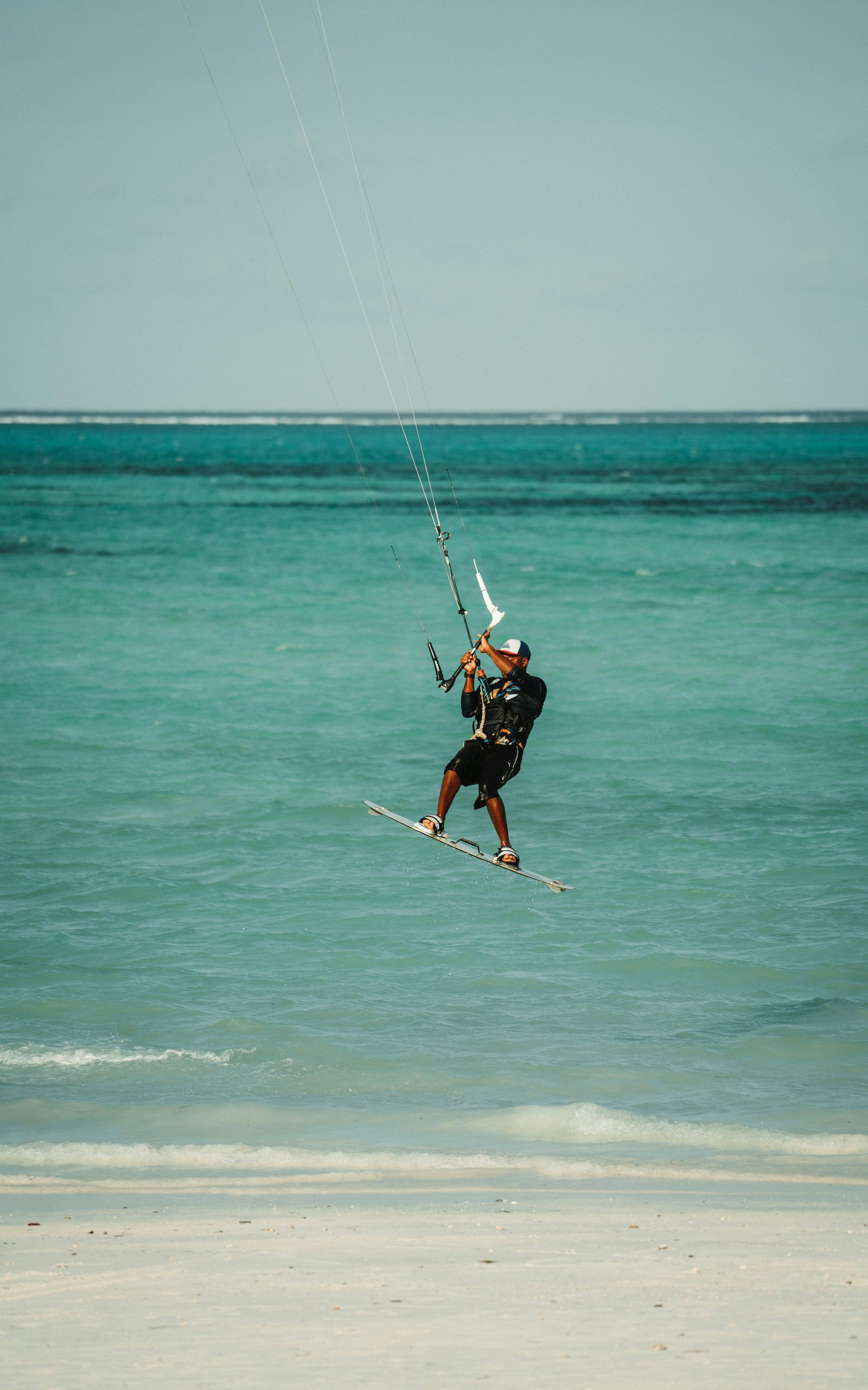 Kitesurfer jumping above turquoise water at Paje Beach, Zanzibar, Tanzania