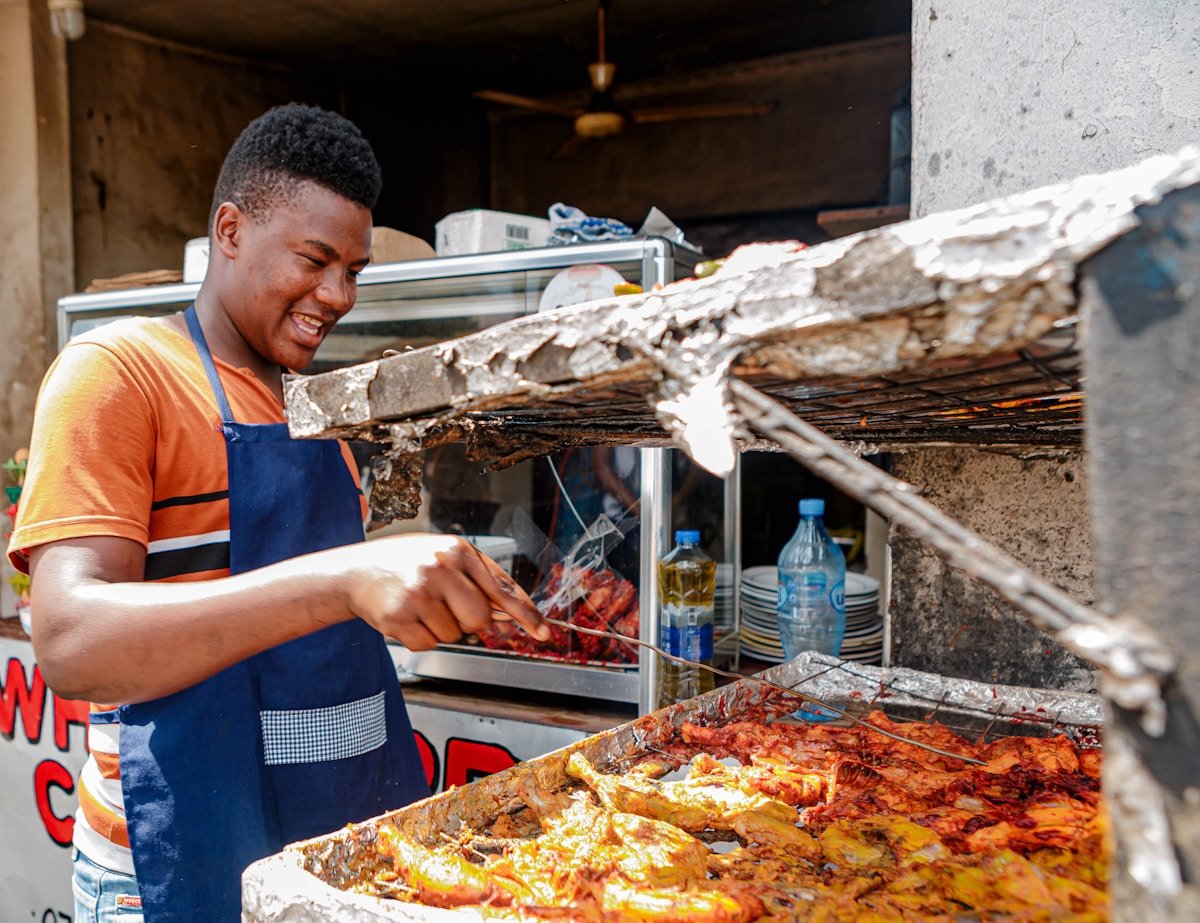Man in apron grilling food at an outdoor street food stall in Tanzania