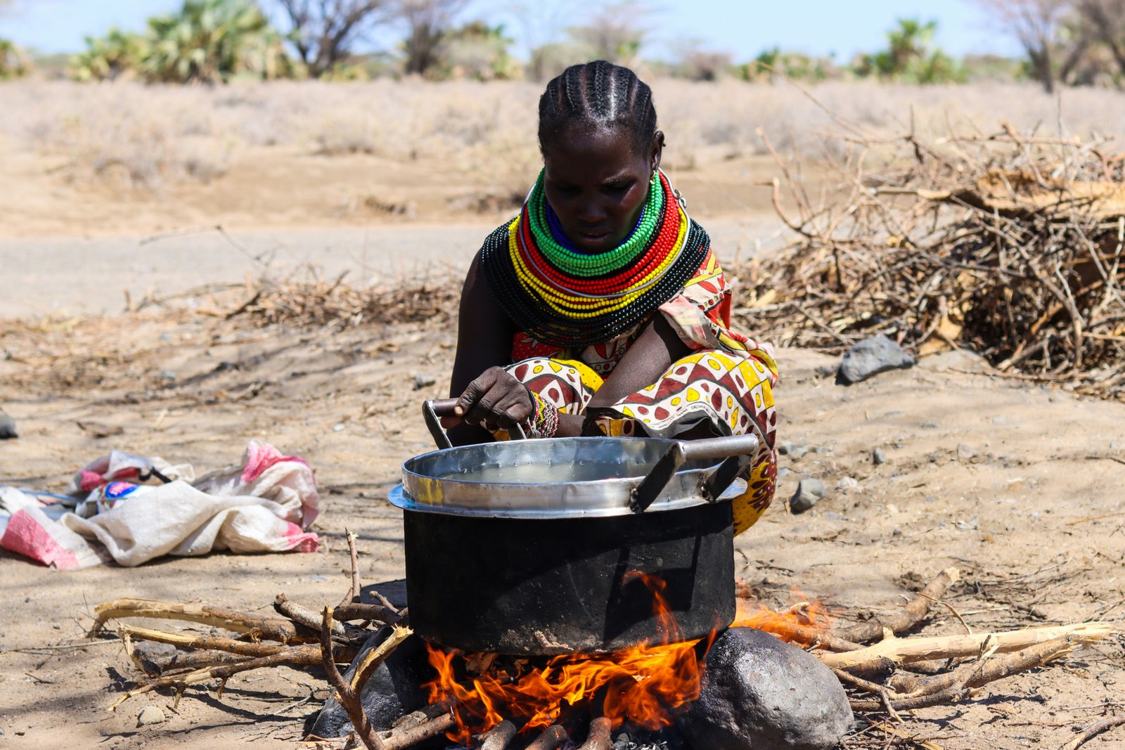 Woman in traditional beaded jewellery cooking over an open fire in East Africa