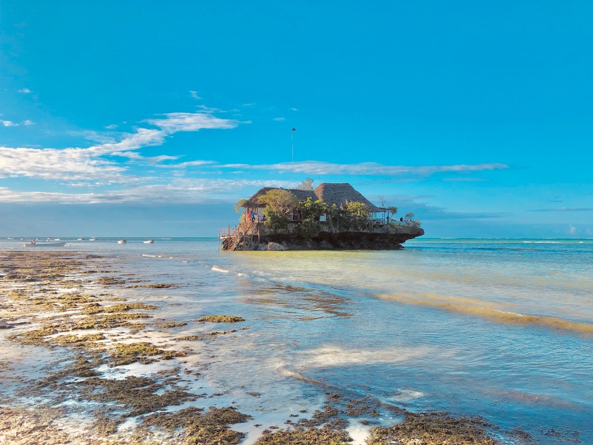 Thatched building on a rock island in the clear shallow sea, Zanzibar, Tanzania