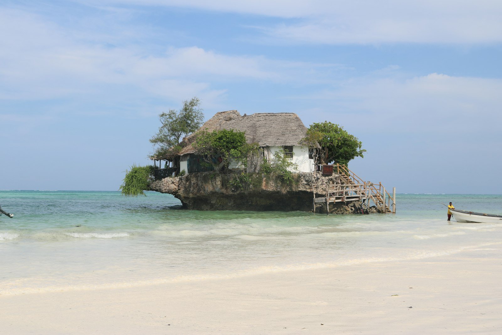 Thatched building on a rocky outcrop surrounded by turquoise Indian Ocean water, Zanzibar