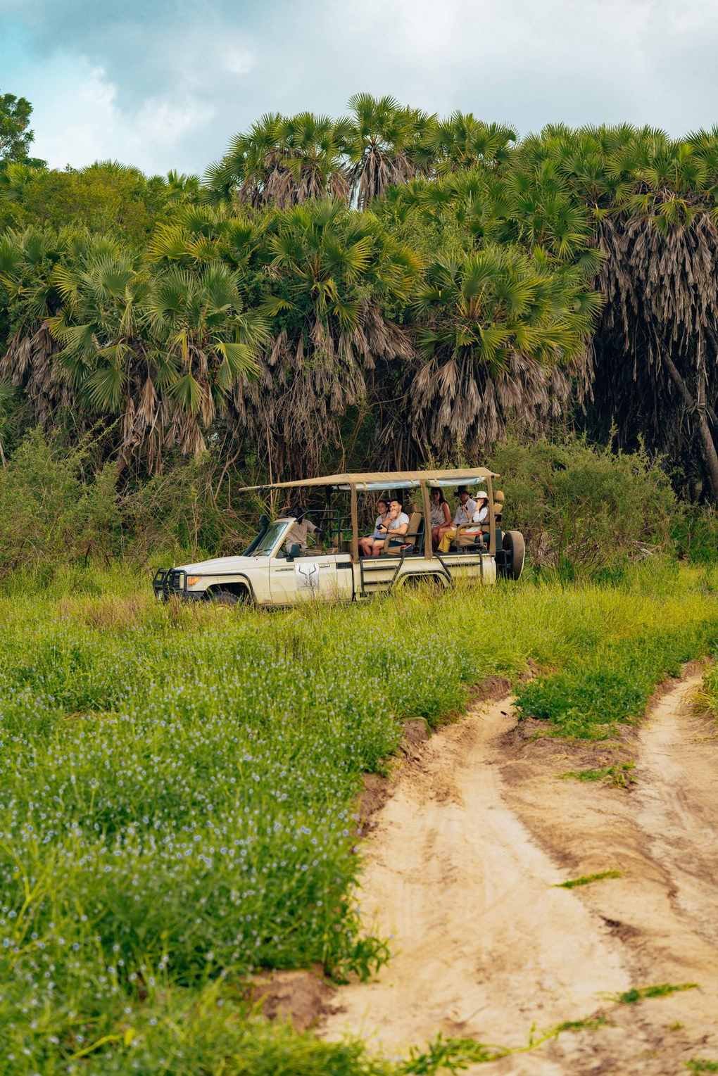 Safari vehicle with tourists on a game drive through lush green vegetation in Tanzania