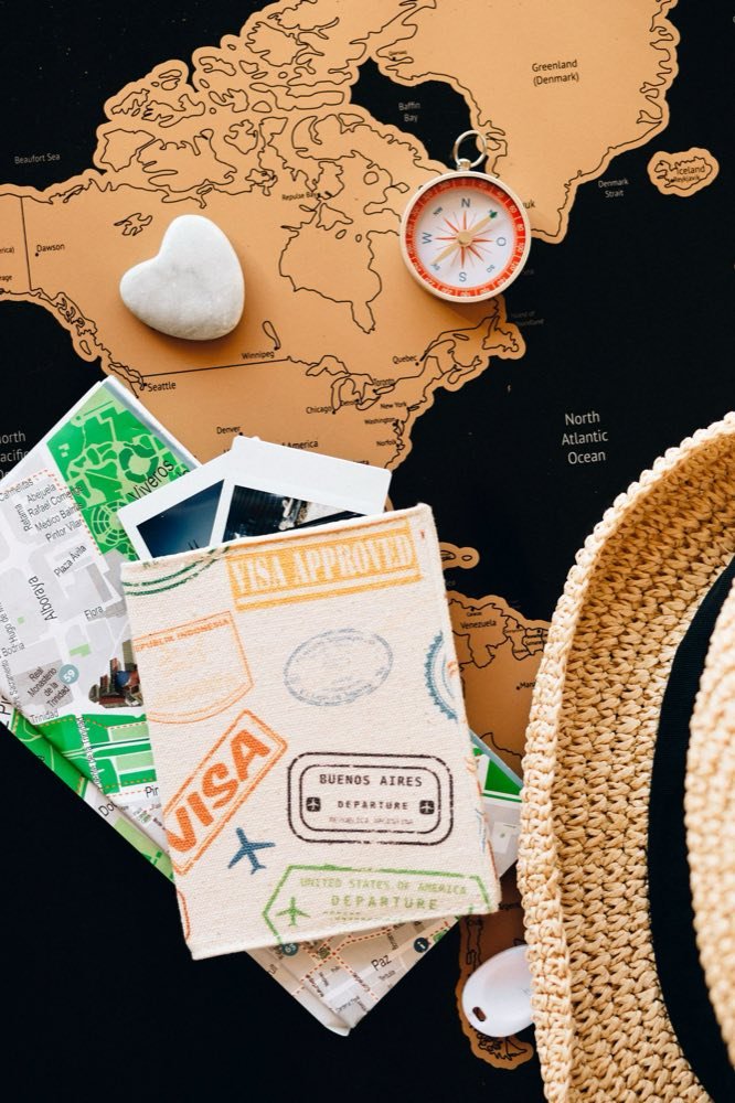 Passport, compass and city map laid out on a world map for trip planning