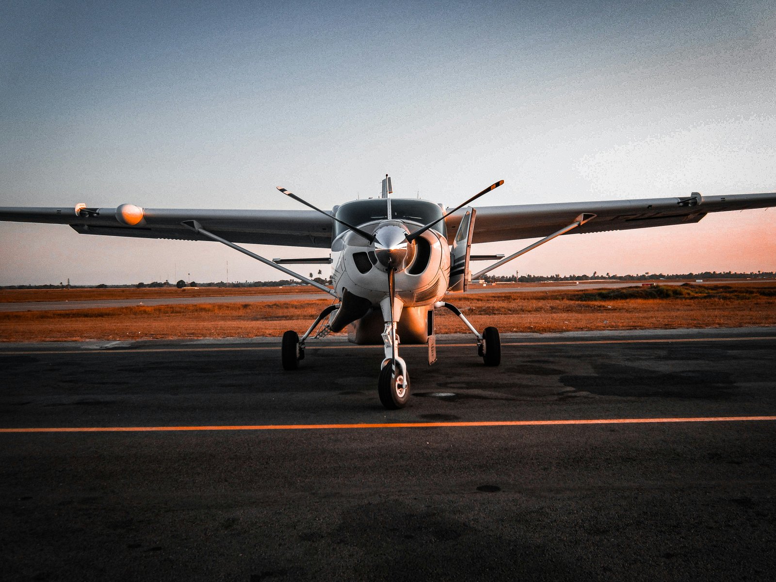 Small propeller aircraft parked on the runway at Dar es Salaam Julius Nyerere International Airport at sunset, Tanzania