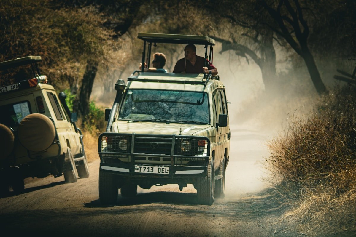 Safari vehicle on a dusty dirt track in the African bush, Tanzania