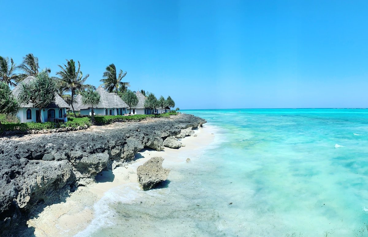 Rocky Zanzibar beach with white-washed coral stone buildings and calm Indian Ocean