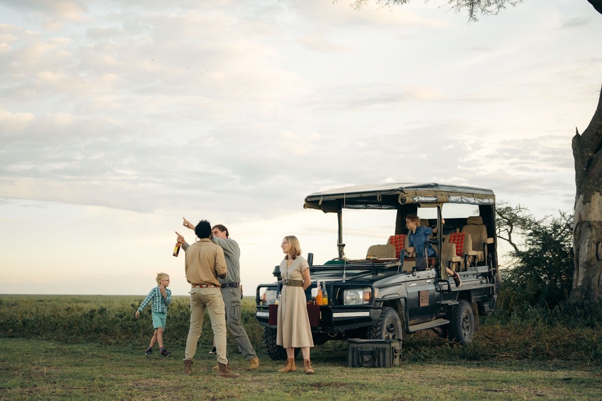 Family on a Tanzania safari, gathered around an open-top game drive vehicle