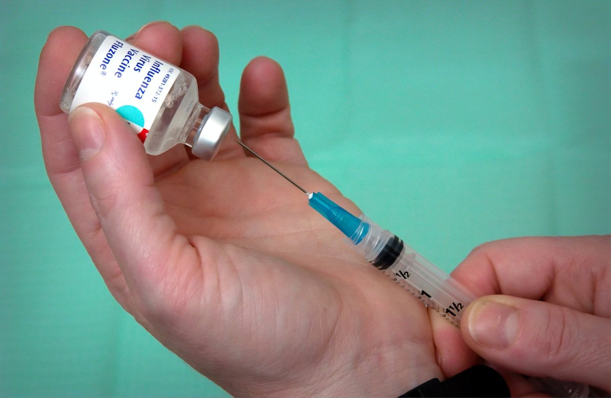 Person holding a syringe and vaccine vial — health preparation for Tanzania travel