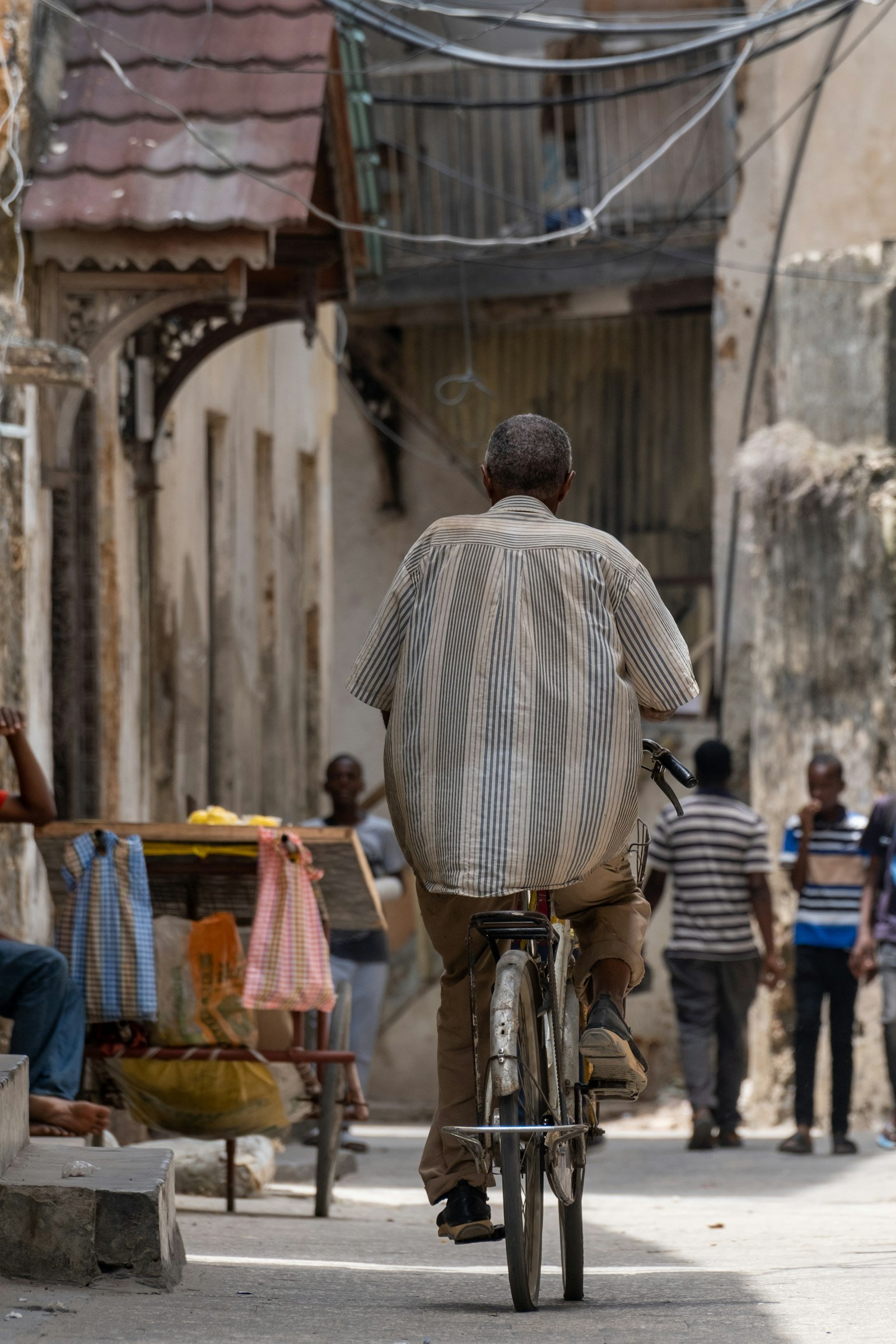 Man cycling through narrow Stone Town alley between historic buildings, Zanzibar