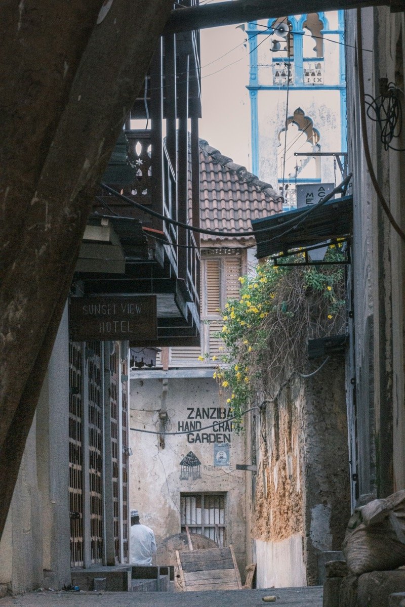 Narrow alley in Stone Town, Zanzibar with historic buildings and carved wood signs