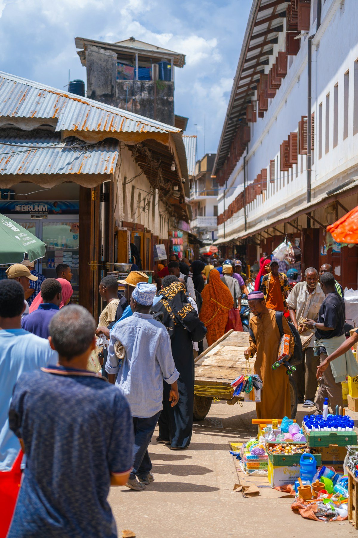 Shoppers browsing a busy outdoor market in Stone Town, Zanzibar, Tanzania